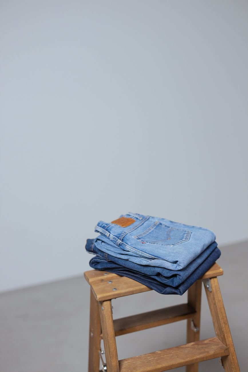 Stack of folded denim jeans against a minimalist backdrop